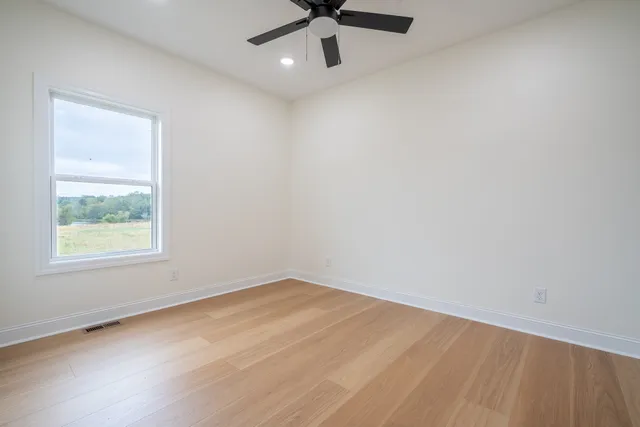 an empty room with a window and a ceiling fan