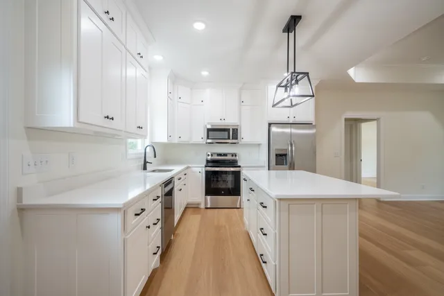 a kitchen with kitchen island granite countertop a sink a counter top space stainless steel appliances and cabinets
