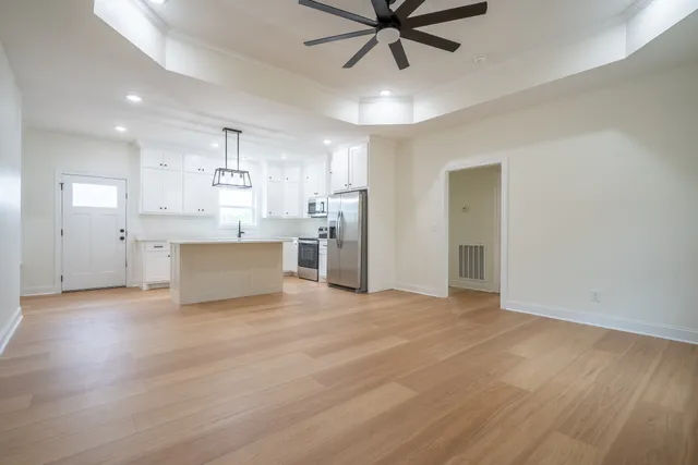 a view of a kitchen with a sink stainless steel appliances wooden floor and a window