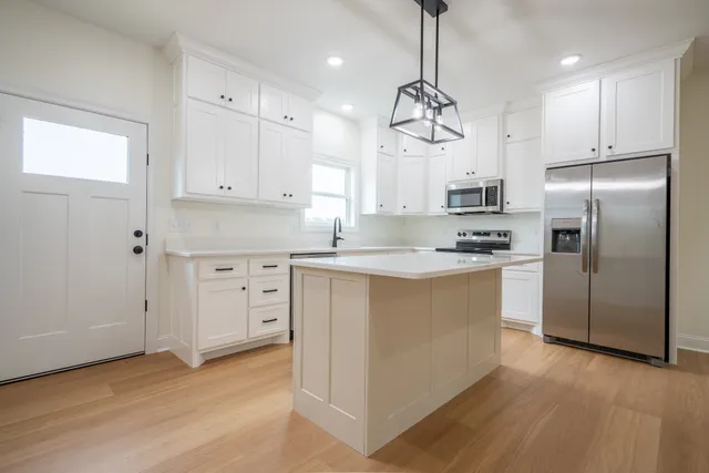 a kitchen with kitchen island a counter top space a sink stainless steel appliances and cabinets