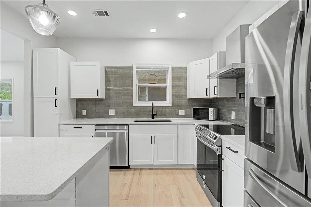 827 Elbert Street Southwest Atlanta, GA 30310 - Photo 6 of 33 a kitchen with a sink a refrigerator a stove and white cabinets