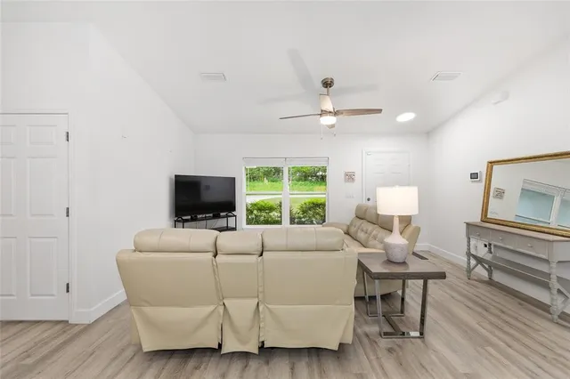 a kitchen with stainless steel appliances a refrigerator a sink a stove and white cabinets with wooden floor