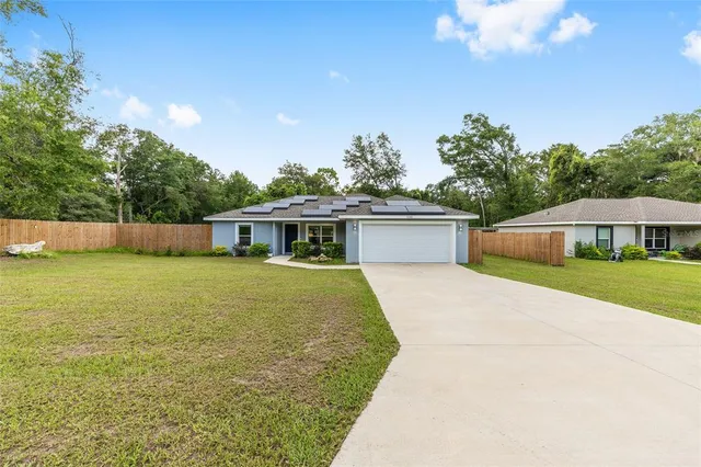 a front view of house with yard and trees in the background
