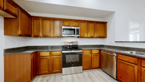 a kitchen with stainless steel appliances granite countertop wooden cabinets a stove top oven a sink and dishwasher