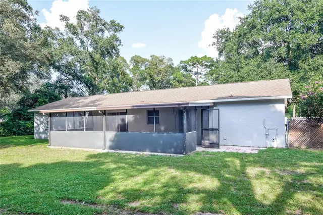 a view of a house with a yard and a large tree
