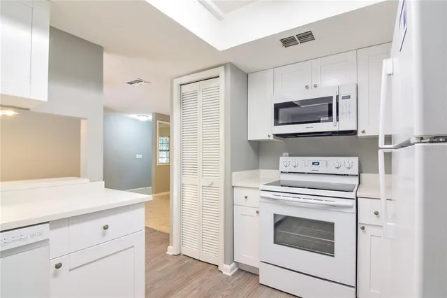 a kitchen with cabinets stainless steel appliances and wooden floor