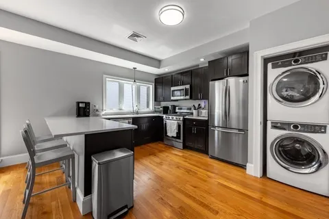 a kitchen with kitchen island a stove a refrigerator and a sink with wooden floor