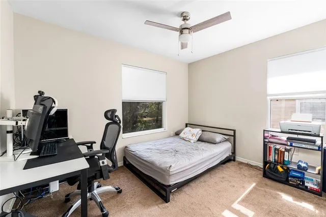 a bedroom with a bed a computer on the desk and a dresser