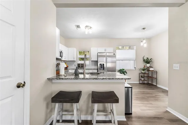 a dining hall with stainless steel appliances granite countertop a dining table and chairs with wooden floor