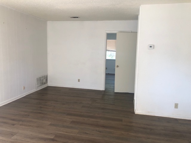 404 West Dittmar Road Austin, TX 78745 - Photo 8 of 15 Empty room with dark wood finished floors and a textured ceiling