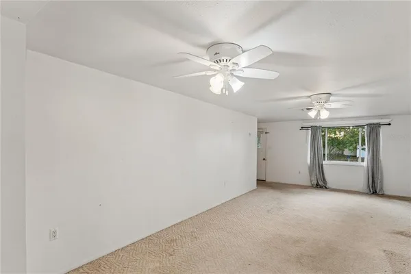 an empty room with a ceiling fan and a window