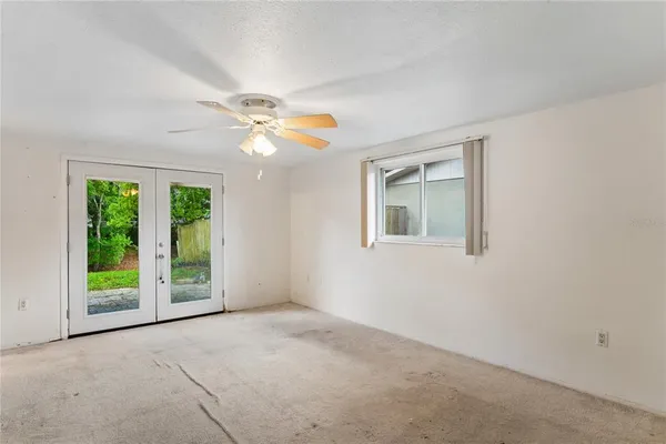 an empty room with windows and fan