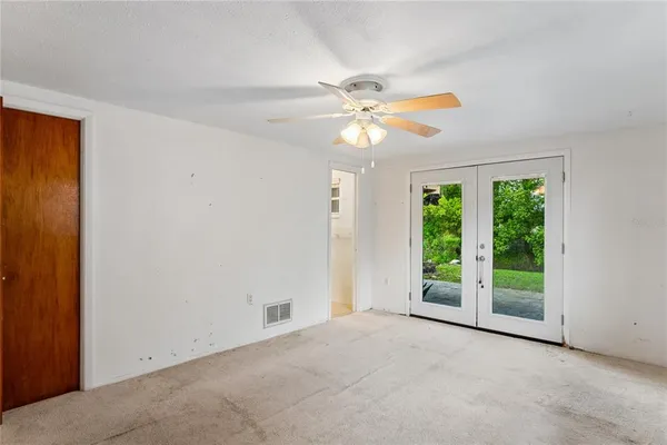an empty room with windows and fan