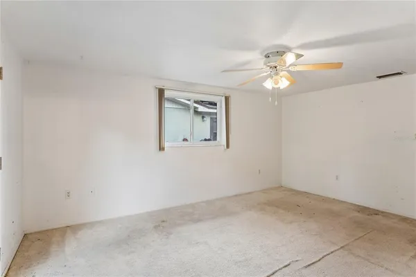 an empty room with a chandelier fan and windows