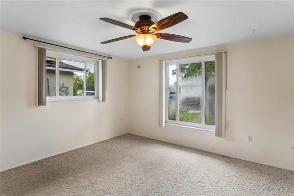 an empty room with window and ceiling fan