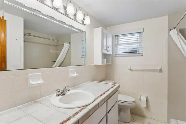 a bathroom with a granite countertop sink a toilet and a mirror
