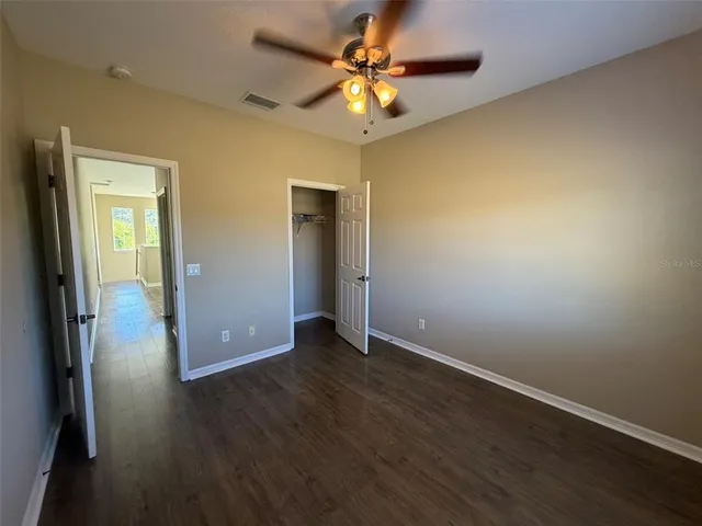 an empty room with wooden floor and a ceiling fan
