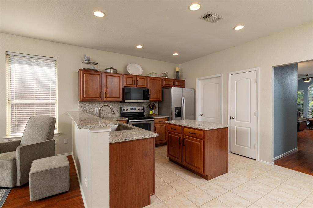 4025 Chisos Rim Trail Fort Worth, TX 76244 - Photo 13 of 40 Kitchen featuring recessed lighting, a central island with a granite countertop, wood cabinetry, and stainless steel appliances