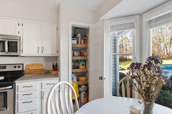 a kitchen with stainless steel appliances granite countertop a stove top oven a sink dishwasher a dining table and chairs with wooden floor