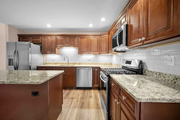 a kitchen with stainless steel appliances granite countertop a sink stove and refrigerator