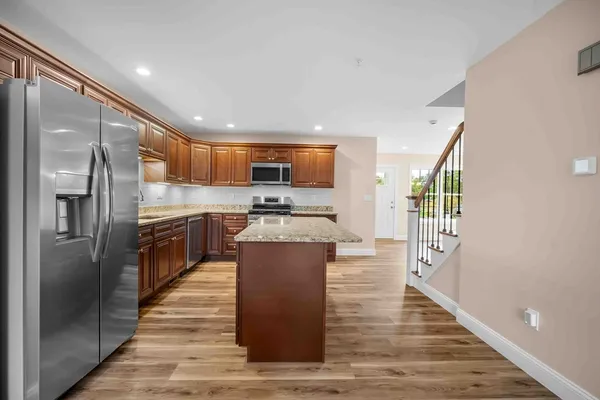 a large kitchen with stainless steel appliances kitchen island a large counter top and a refrigerator