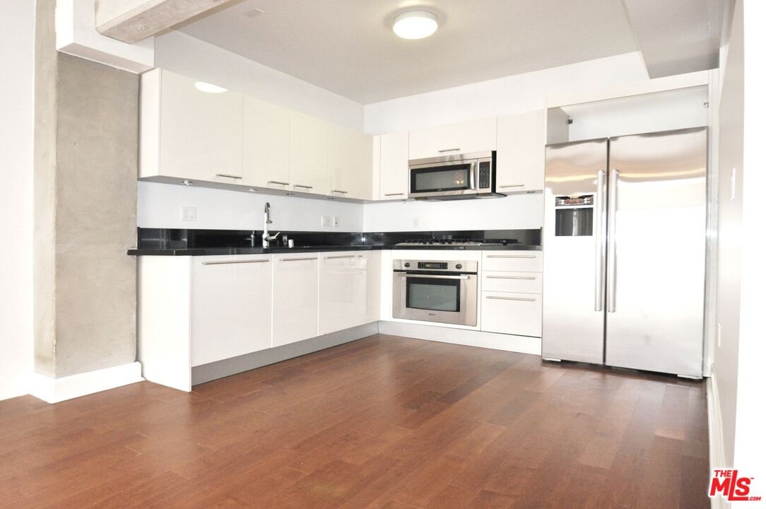 416 South Spring Street, Unit 805 Los Angeles, CA 90013 - Photo 6 of 24 a kitchen with stainless steel appliances a stove a microwave and a refrigerator