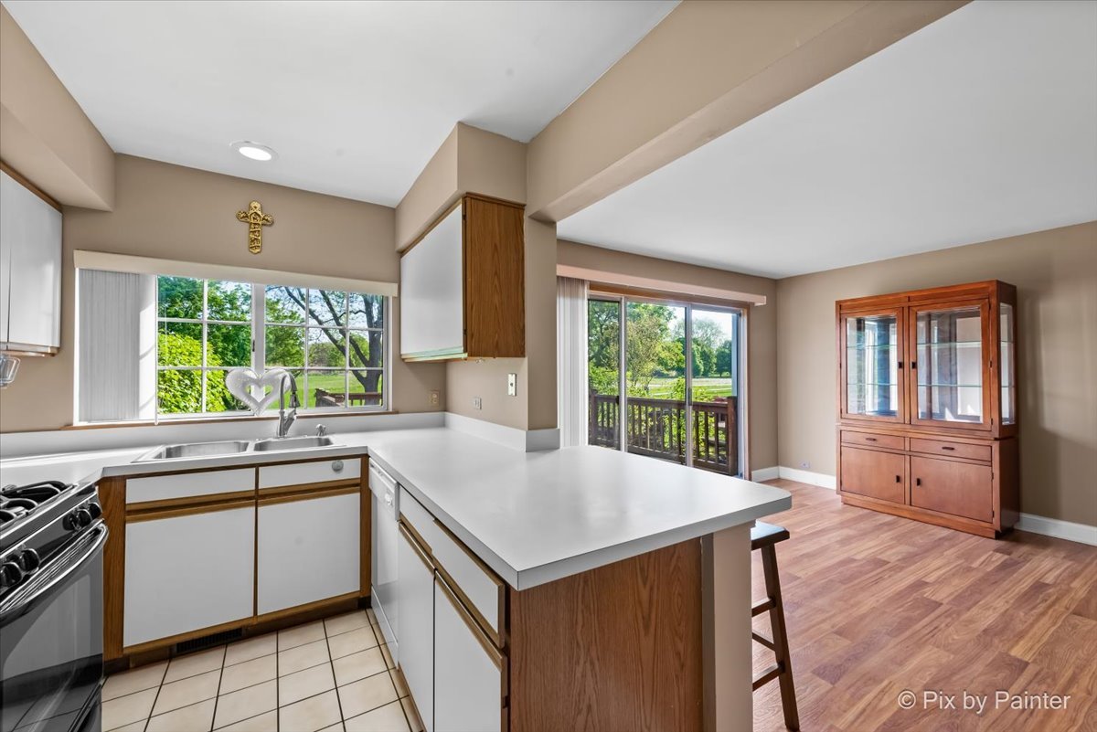 1664 Pebble Beach Circle Elgin, IL 60123 - Photo 8 of 24 a kitchen with a stove a sink a microwave oven and a dining table with wooden cabinet