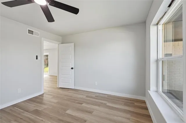 a view of an empty room with wooden floor and window