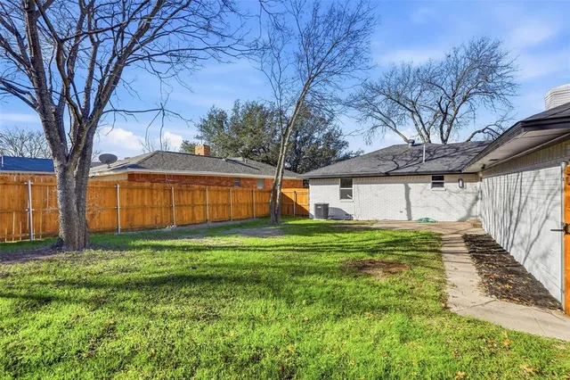 a backyard of a house with wooden fence and large trees
