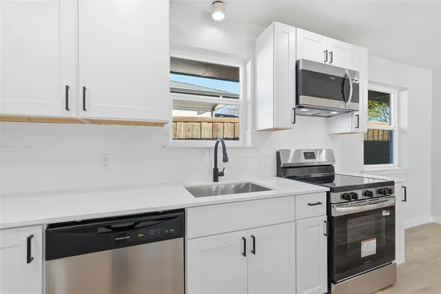 a kitchen with stainless steel appliances a sink stove and microwave