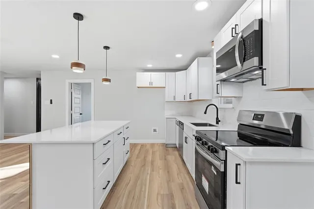 a kitchen with stainless steel appliances granite countertop a sink a stove and a refrigerator