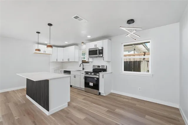 a kitchen with stainless steel appliances granite countertop a stove top oven a sink dishwasher and a refrigerator with wooden floor