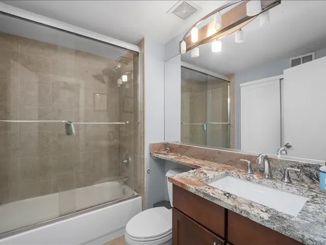 a bathroom with a granite countertop sink toilet and shower