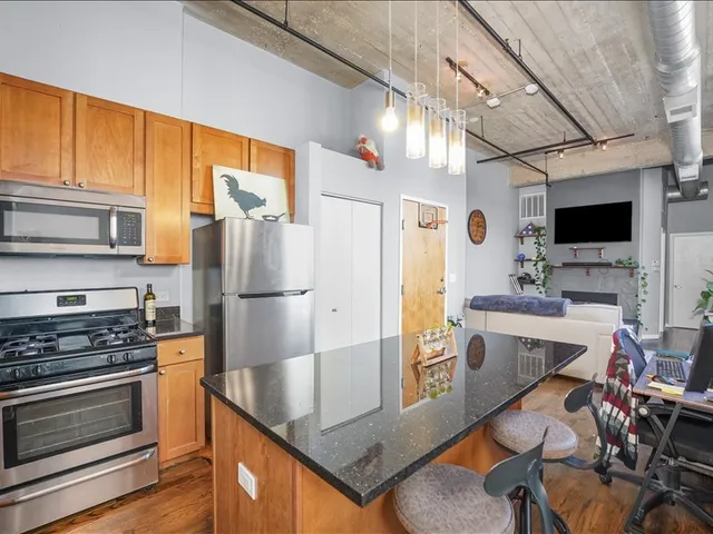 a kitchen with stainless steel appliances kitchen island granite countertop a stove refrigerator and microwave
