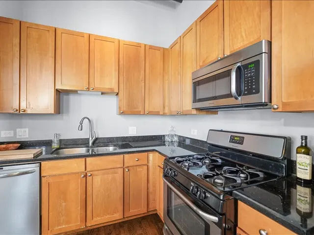 a kitchen with stainless steel appliances granite countertop a stove a sink dishwasher and microwave with wooden cabinets