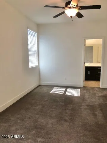 an empty room with a window and chandelier fan