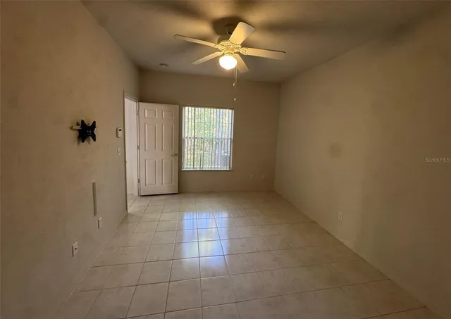 an empty room with windows and fan