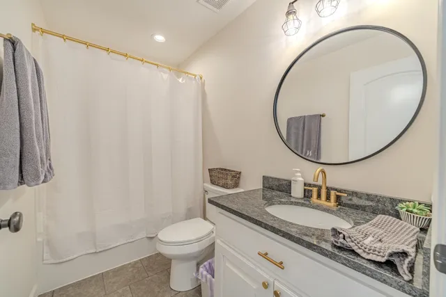 a bathroom with a granite countertop sink mirror vanity and a toilet