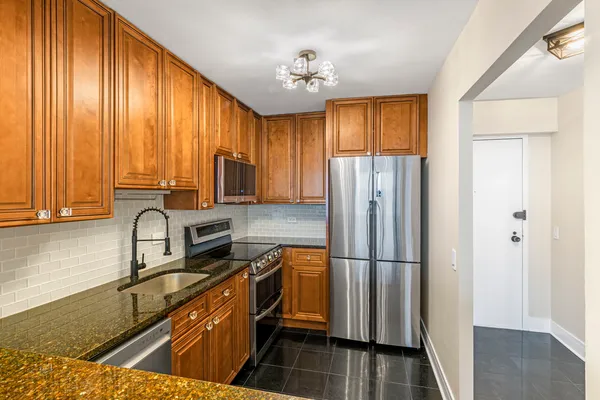 a kitchen with granite countertop stainless steel appliances a refrigerator microwave and stove top oven