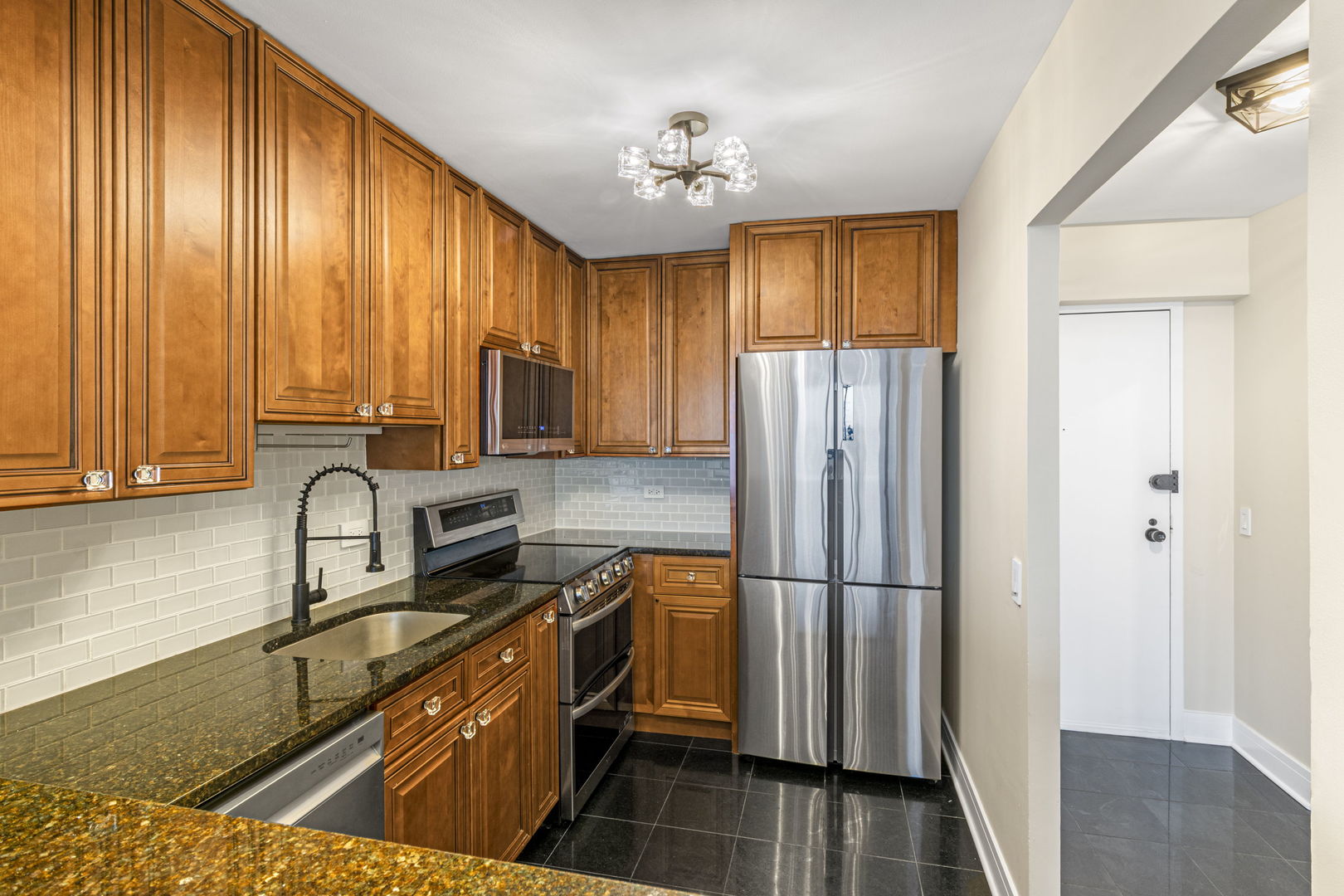 5415 North Sheridan Road, Unit 915 Chicago, IL 60640 - Photo 6 of 28 a kitchen with granite countertop stainless steel appliances a refrigerator microwave and stove top oven
