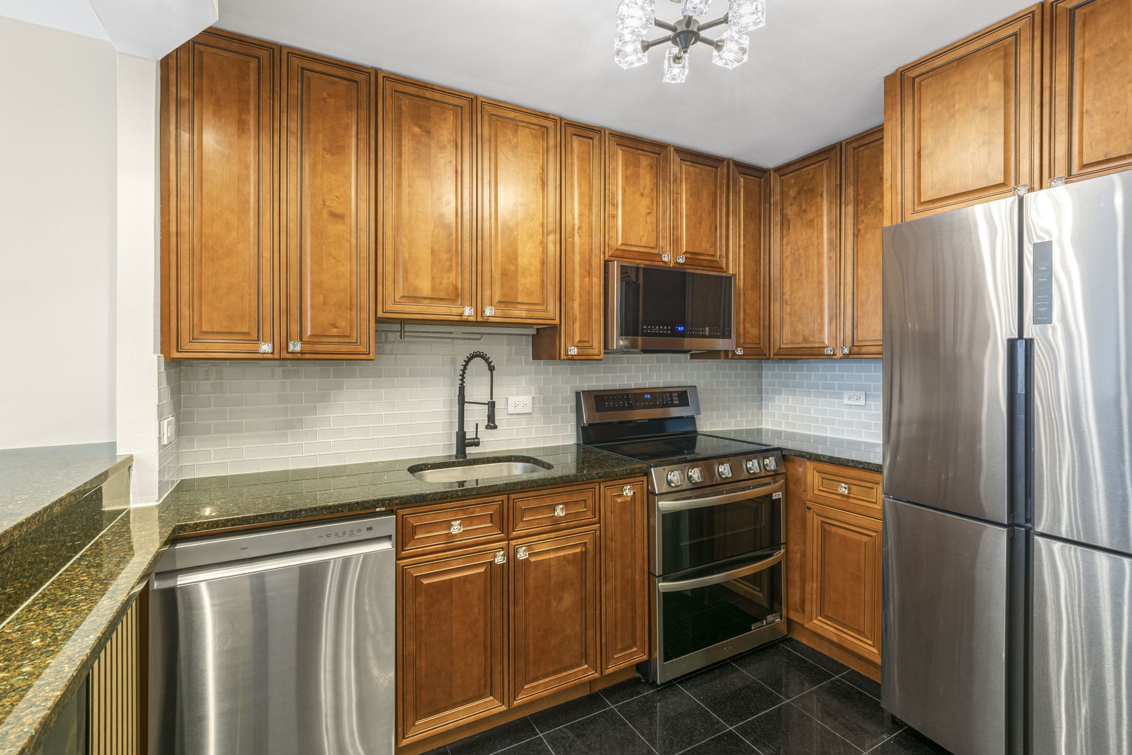 5415 North Sheridan Road, Unit 915 Chicago, IL 60640 - Photo 7 of 28 a kitchen with stainless steel appliances granite countertop a refrigerator stove microwave and sink