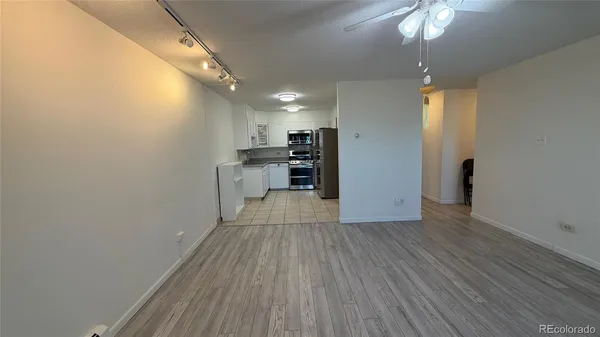 an empty room with wooden floor and a kitchen