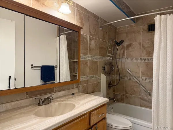 a bathroom with a sink vanity granite toilet and shower