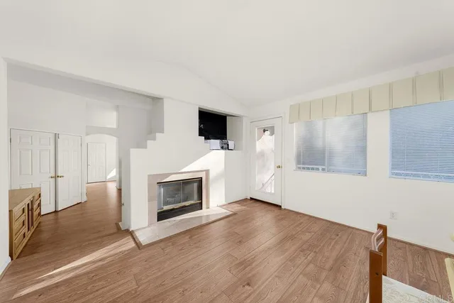a view of a livingroom with wooden floor and a fireplace
