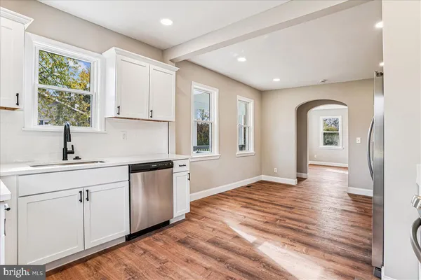a kitchen with stainless steel appliances granite countertop a sink and window with wooden floors