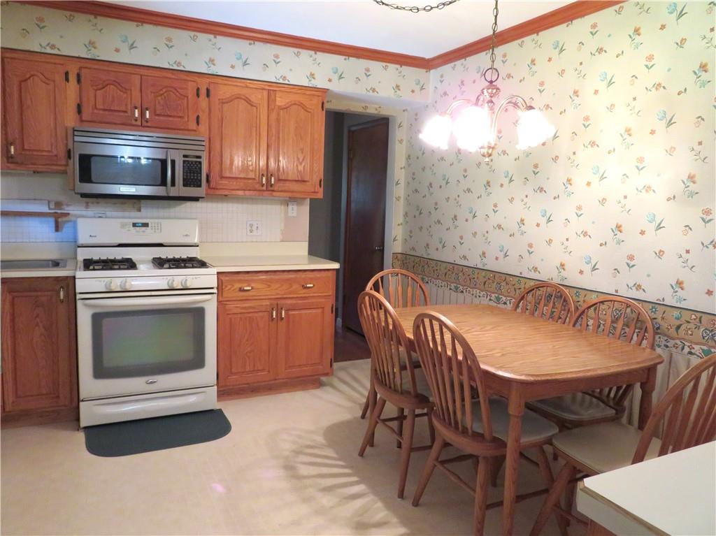 736 Beaver Street Rochester, PA 15074 - Photo 7 of 24 a kitchen with granite countertop a stove top oven a sink dishwasher a dining table and chairs with wooden floor