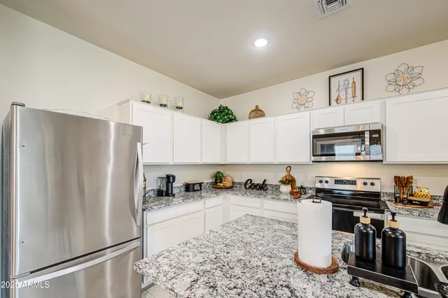 a kitchen with stainless steel appliances granite countertop a refrigerator a stove and a sink