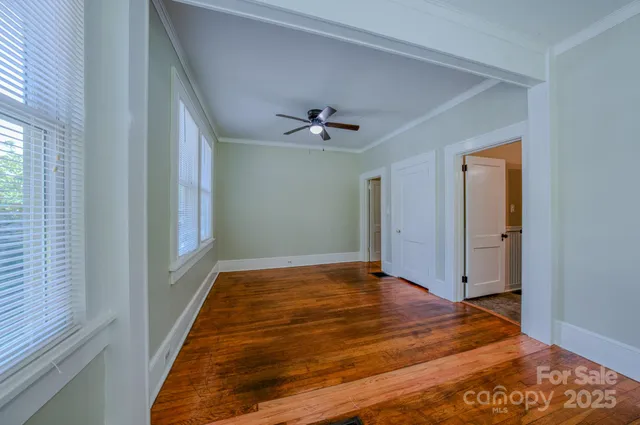a view of empty room with wooden floor and fan
