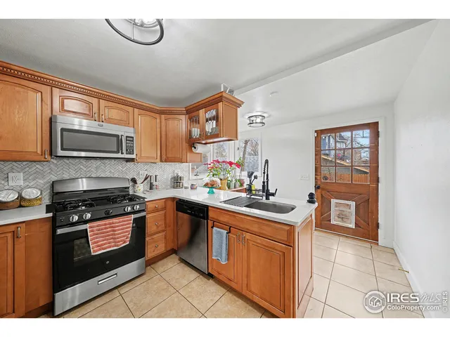 a kitchen with stainless steel appliances granite countertop a stove top oven a sink dishwasher a dining table and chairs with wooden floor