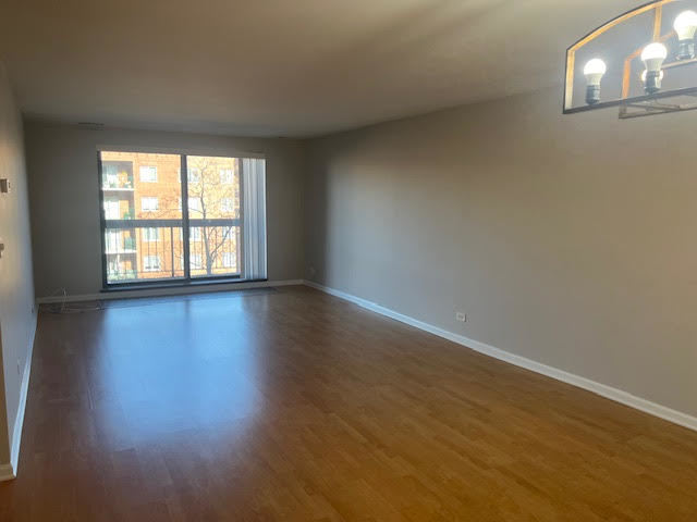 711 South River Road, Unit 511 Des Plaines, IL 60016 - Photo 4 of 23 an empty room with wooden floor and windows